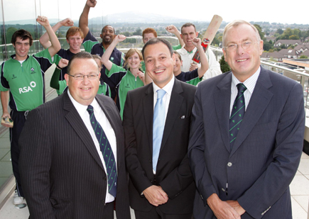 From Left: Philip Smith, (RSA Ireland Chief Executive), Warren Deutrom (Cricket Ireland Chief Executive), and David Williams (Cricket Ireland Chairman) - Background are members of the Ireland Senior Men, Women and Under 19 squads. (C) MAXWELL PHOTOGRAPHY